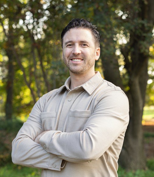 Mason Anglin, PsyD, LMFT, standing outdoors under oak trees